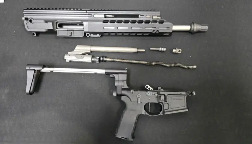 Rozłożony karabinek AR-15: górna i dolna część komory zamkowej, lufa, suwadło, sprężyna powrotna i inne części.