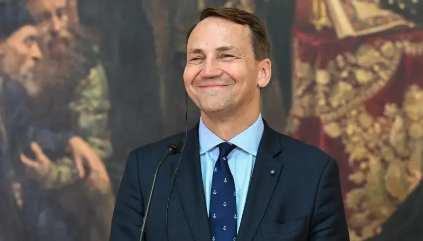 Uśmiechnięty Sikorski, który polityk? W tle obraz z postaciami.