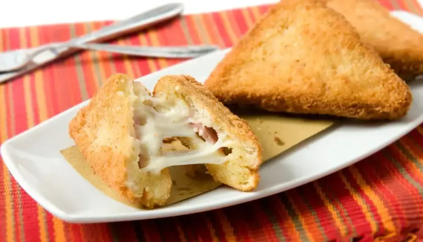 Mozzarella in carrozza in friggitrice ad aria: triangoli dorati e croccanti con cuore filante di mozzarella e prosciutto.