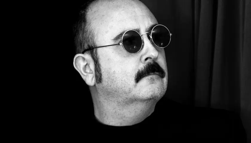 Carlos Areces, con su pareja de gafas redondas y bigote, posa con misterio.