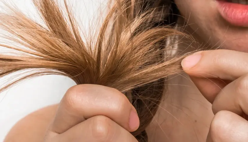 Mujer examinando su cabello fino, buscando soluciones para aumentar densidad capilar mujer.