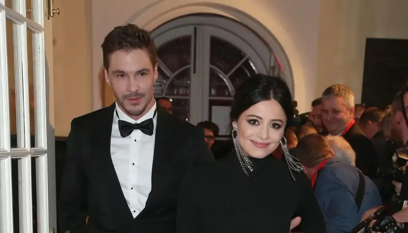 Adriana Kalska z partnerem na czerwonym dywanie, uśmiechnięci i eleganccy.