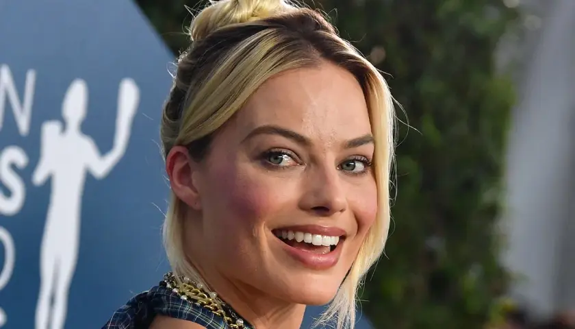 Margot Robbie, l'actrice qui incarne Harley Quinn, rayonne avec un chignon blond et un sourire éclatant.