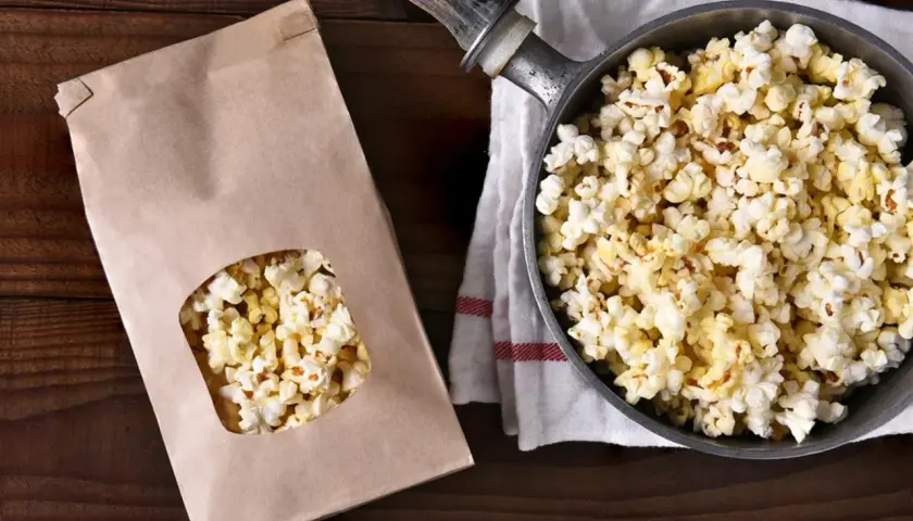 Jak zrobić popcorn w garnku? Świeżo przygotowany popcorn w garnku i papierowej torbie, gotowy do chrupania.