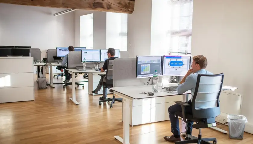 Bureau moderne avec employés travaillant sur des ordinateurs. Un homme utilise un service de bureau cloud pour gérer des données.