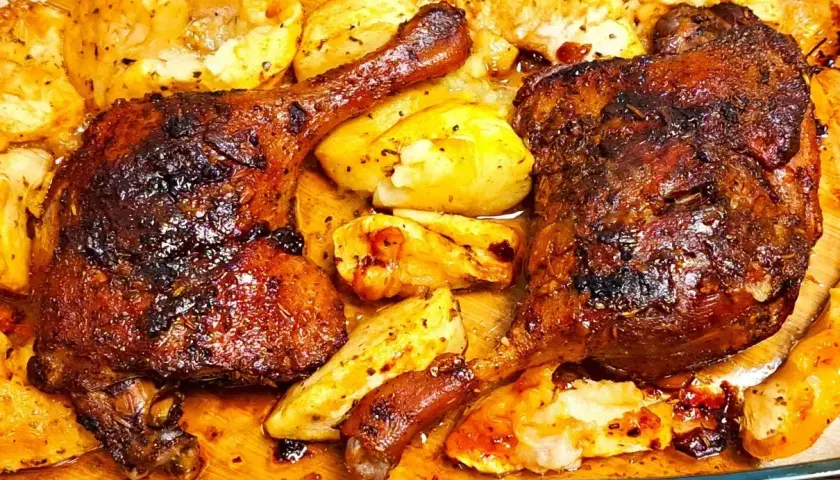 Pyszne, chrupiące udka z kaczki z piekarnika, pieczone z ziemniakami. Skórka lśni od sosu, a ziemniaki są idealnie przypieczone.