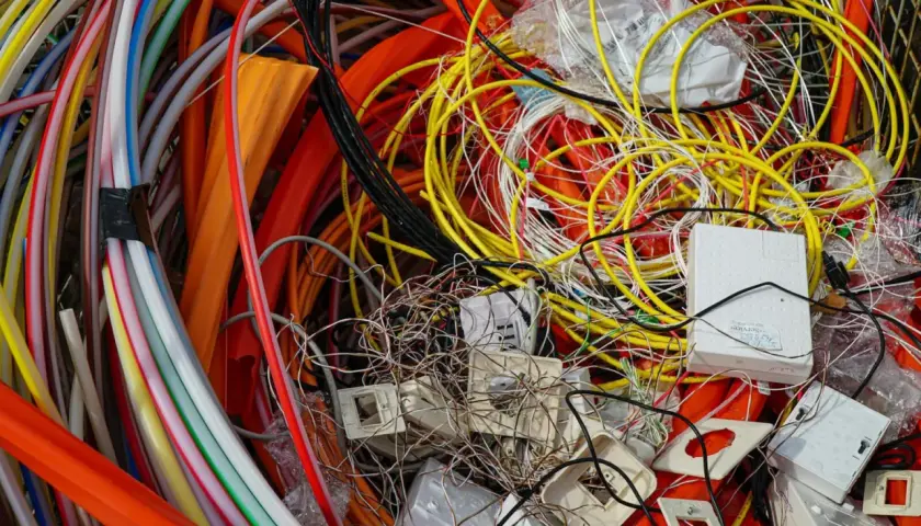 Plątanina kolorowych kabli, przewodów i białych puszek, przypominająca elektrośmieci.