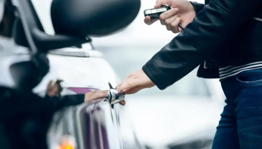 Mano abre la puerta del coche con la llave en la otra mano. La llave del coche gira pero no arranca.