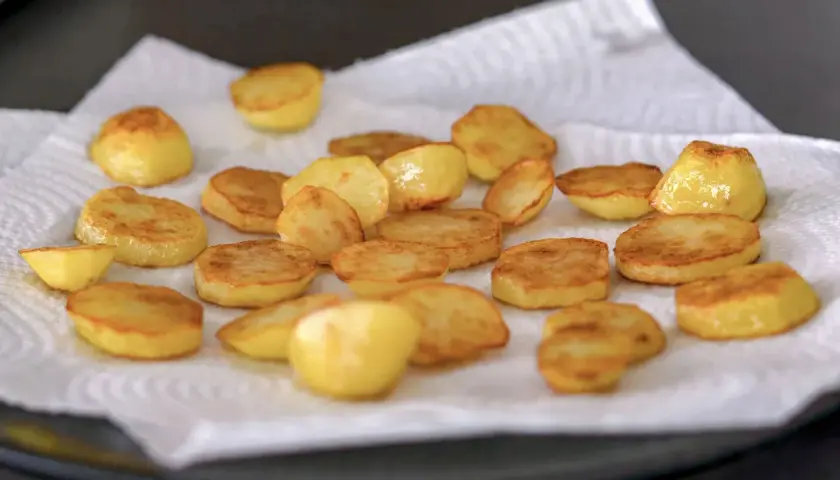 Patatas al horno recién hechas, doradas y crujientes, reposando sobre papel absorbente. ¡Listas para disfrutar!