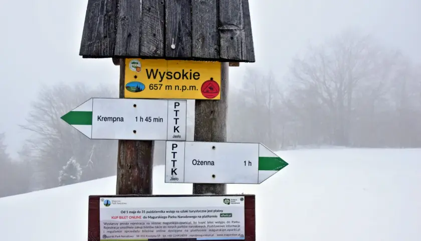 Magurski Park Narodowy atrakcje: drogowskazy szlaków do Krempnej (1h 45min) i Ożennej (1h), szczyt Wysokie (657 m n.p.m.). Informacja o płatnym wstępie.
