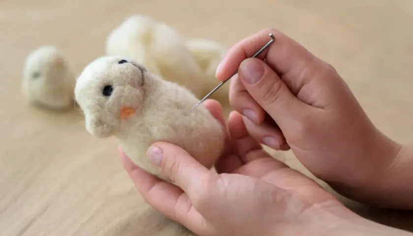 Hände formen mit Nadel und Wolle ein süßes Tierchen. Perfekt für trockenfilzen mit Kindern.