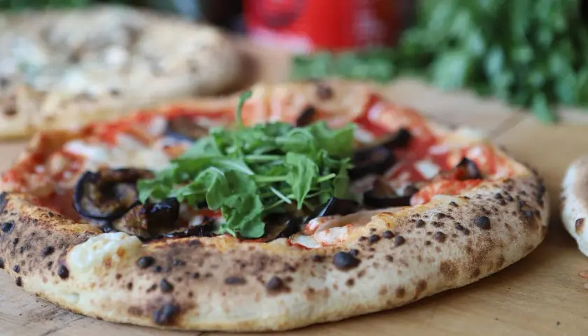 Eine köstliche neapel pizza mit Auberginen und Rucola, frisch aus dem Ofen.