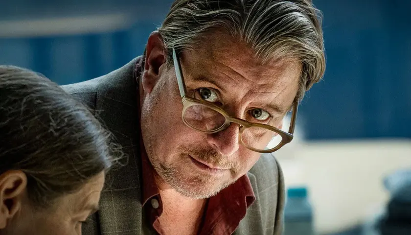 En man med glasögon lutar sig framåt, intensiv blick. En ny dansk serie på TV4.