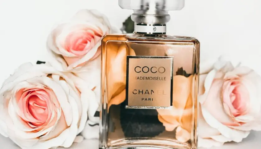 Flakon perfum Chanel Coco Mademoiselle otoczony różowymi różami.