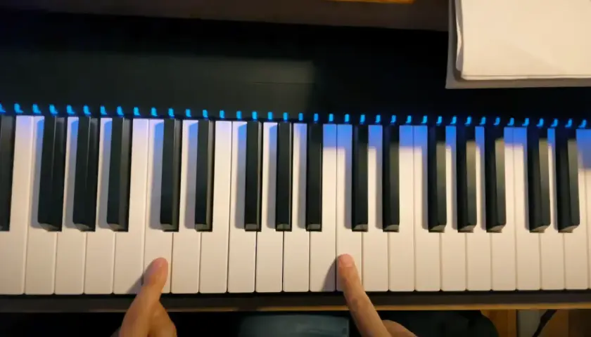 Les doigts effleurent les touches d'un **dièse clavier** illuminé de bleu, prêt à jouer une mélodie.