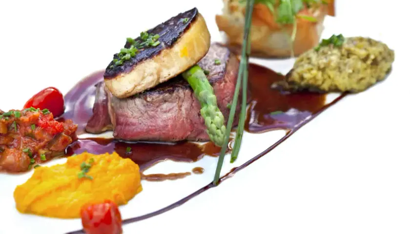 Un steak tendre surmonté de foie gras poêlé, accompagné de purée de patates douces et d'une ratatouille. Un plat qui invite à se demander quoi boire avec du foie gras.