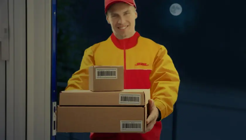 DHL-Bote liefert Pakete bei Nacht aus, der Mond scheint.