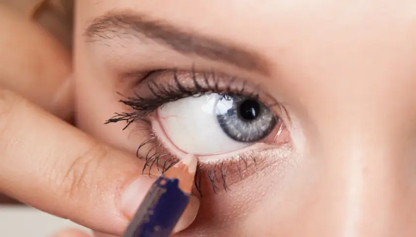 Aplicando delineador en la linea de agua del ojo, creando un look intenso.