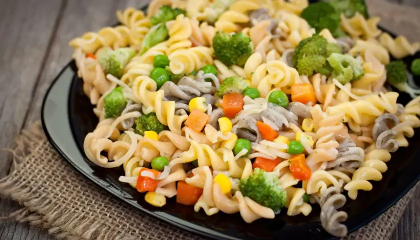 Deliciosa ensalada de pasta vegana con brócoli, guisantes, zanahoria y maíz. Un plato colorido y saludable.