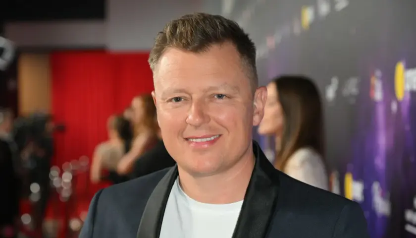 Uśmiechnięty Rafał Brzozowski na ściance. Wiele osób zastanawia się, ile lat ma Rafał Brzozowski, ale na zdjęciu tego nie widać.