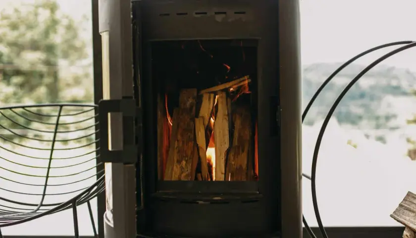 Poêle à bois allumé, avec une prise d'air poele à bois obligatoire pour une combustion optimale. Le feu crépite joyeusement.