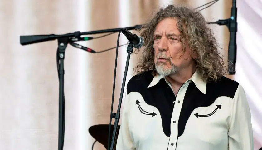 Robert Plant, jeden z legendarnych członków Led Zeppelin, na scenie z charakterystyczną fryzurą i koszulą.