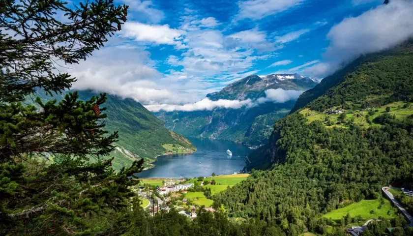 Widok na fiord podczas wycieczki do Norwegii. Statek wycieczkowy wpływa do malowniczej doliny otoczonej zielonymi górami.