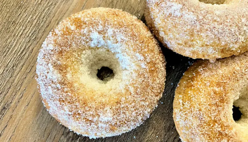 Trois donuts dorés, saupoudrés de sucre, prêts à être dégustés. Une recette donuts simple et gourmande.