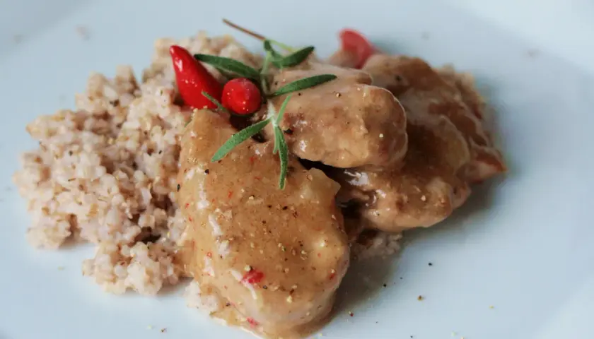 Polędwiczki wieprzowe w sosie własnym, danie Ani gotuje, podane z kaszą i ozdobione papryczką chili i rozmarynem.
