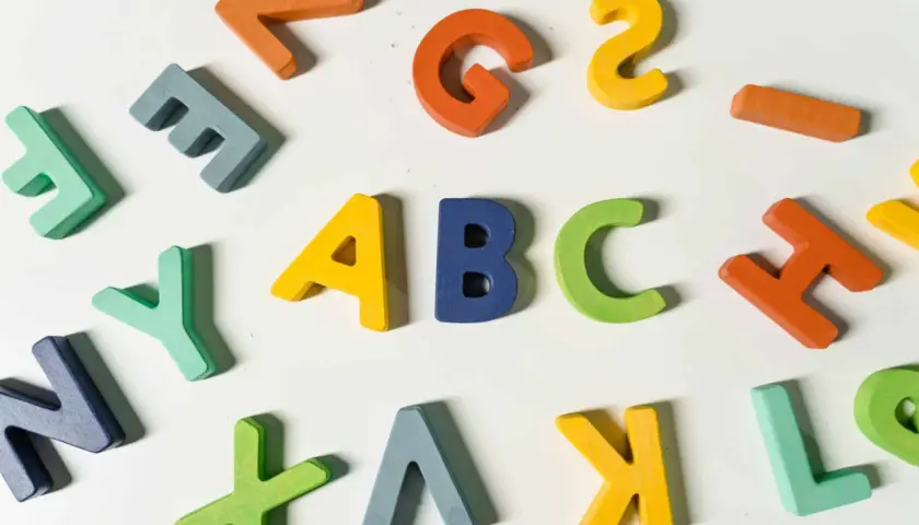 Kolorowe, drewniane litery układają się w napis "ABC", idealne do nauki angielskiego na poziomie a1.