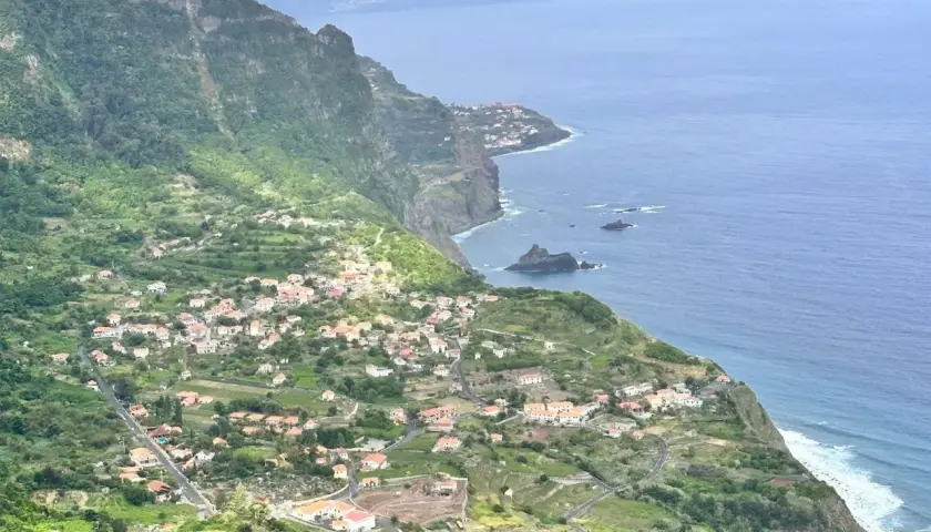 Grüne Hänge mit kleinen Häusern, die sich an die Küste schmiegen. Ein malerischer Anblick, der zu den Madeira Geheimtipps gehört.