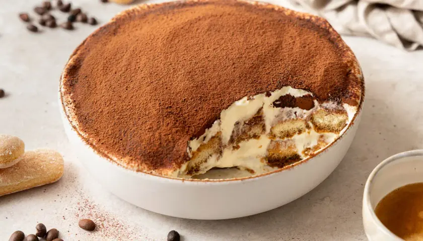 Un invitante tiramisù, una soffice mousse al cioccolato cosparsa di cacao, con savoiardi inzuppati e crema.