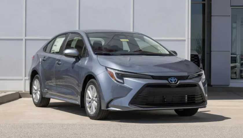 Grigio Toyota Corolla, un'auto a metano ecologica, parcheggiata davanti a un edificio moderno.