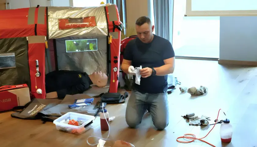 Ćwiczenie kwalifikowanej pierwszej pomocy. Instruktor przygotowuje materiały, obok manekin do nauki.