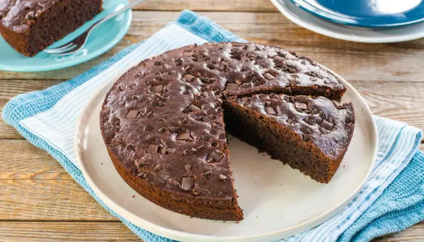 Deliziosa torta vegana al cioccolato, cosparsa di gocce e pezzi di cioccolato fondente, pronta per essere gustata.