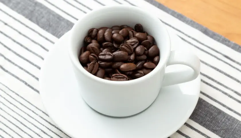 Eine Tasse gefüllt mit gerösteten Kaffeebohnen. Die Frage: filterkaffee wieviel gramm pro liter?