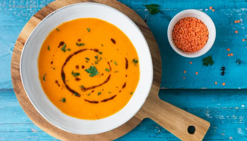Ciorba turca ricetta originale: zuppa di lenticchie rosse cremosa, guarnita con prezzemolo e olio.