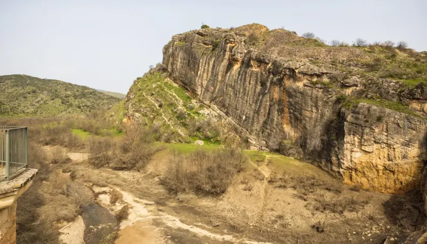 Escalada en la **ruta cañones del rio lozoya**. Un paisaje rocoso con un río seco y vegetación escasa.