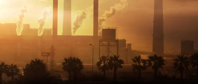 Paisaje industrial con chimeneas humeantes al atardecer. Ojalá se pudiera aplicar **limpieza con ozono** para purificar el aire.