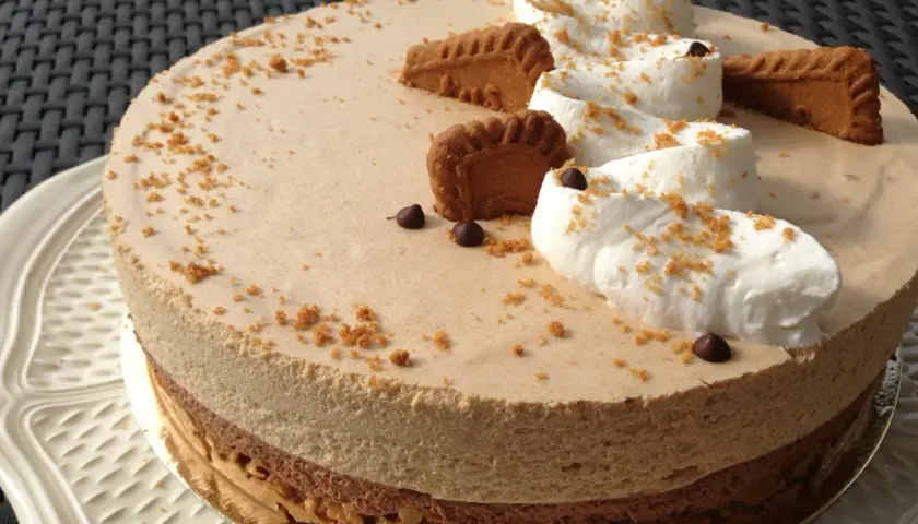 Gâteau à la mousse légère, décoré de crème fouettée, de pépites de chocolat et de biscuits speculoos croustillants.