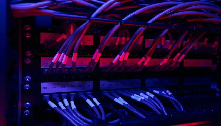 Red y azul iluminan un rack de servidores con un intrincado **cableado horizontal**.