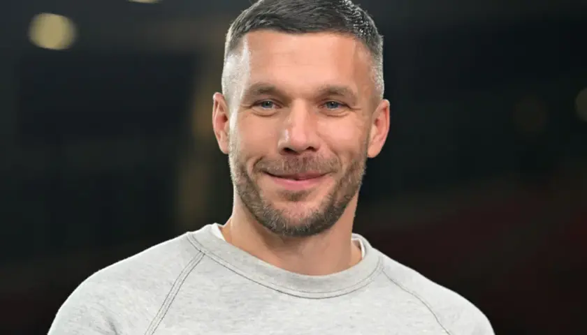Uśmiechnięty Łukasz Podolski w szarej bluzie. Jego kariera piłkarska i biznesy budują imponujący lukas podolski majątek.