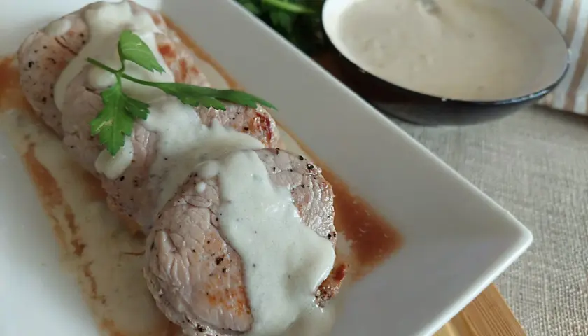 Solomillo de cerdo bañado en una cremosa salsa de queso azul, decorado con perejil fresco. ¡Un manjar para los sentidos!