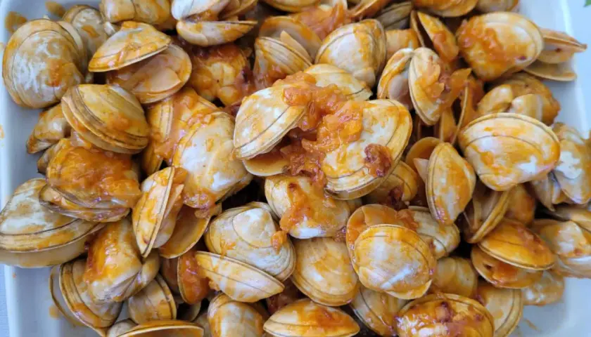Un plato lleno de percebe gallego cocinado en una salsa anaranjada.