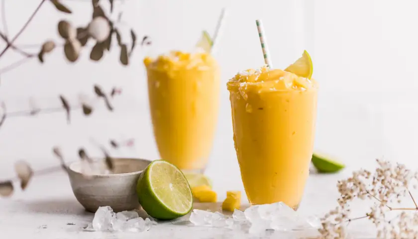 Zwei cremige Mango-Lassis mit Limette und Kokosraspeln. Perfekt nach dem getrocknete Mango einweichen.