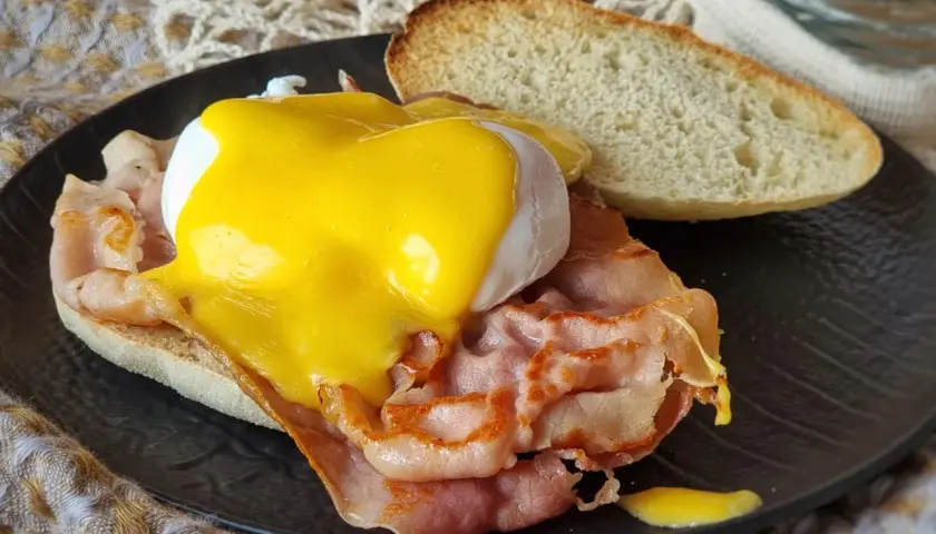 Deliciosos huevos benedictinos con jamón, huevo escalfado y salsa holandesa sobre pan tostado. Un clásico desayuno.