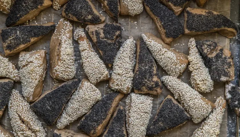 En hög med nybakade, trekantiga bröd med sesamfrön och vallmofrön. De ser ut som en härlig, gammal deg som väntar på att bli uppäten.