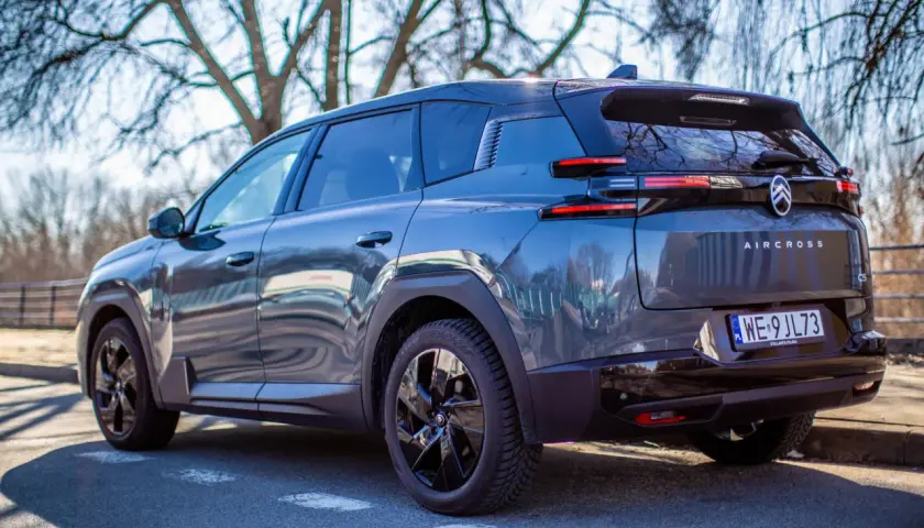 Ciemnoszary Citroën C5 Aircross Hybrid zaparkowany pod drzewami. Widok z tyłu, z tablicą rejestracyjną WE 9JL73.