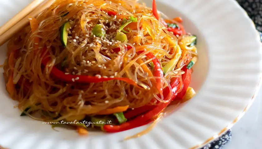 Spaghetti di soia con verdure colorate, un piatto leggero e gustoso, guarnito con semi di sesamo.