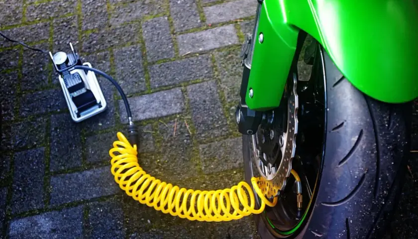 Compresor portátil conectado a la rueda de una moto para hinchar neumáticos con nitrógeno.